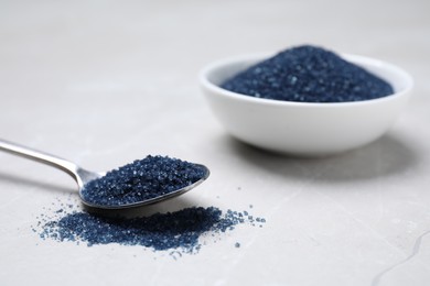 Bowl and spoon with blue food coloring on light grey table. Space for text