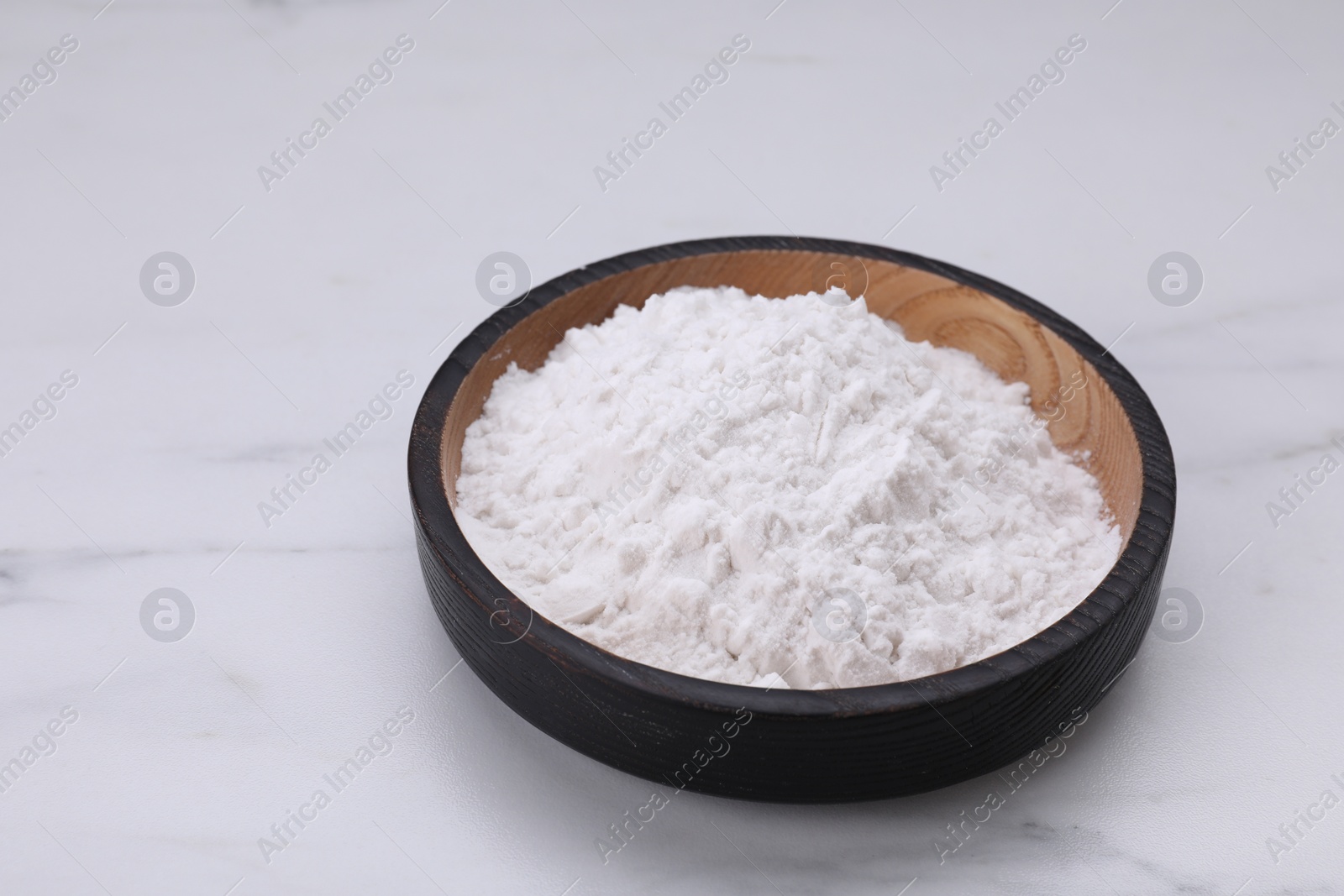 Photo of Wooden bowl of natural starch on white marble table, space for text