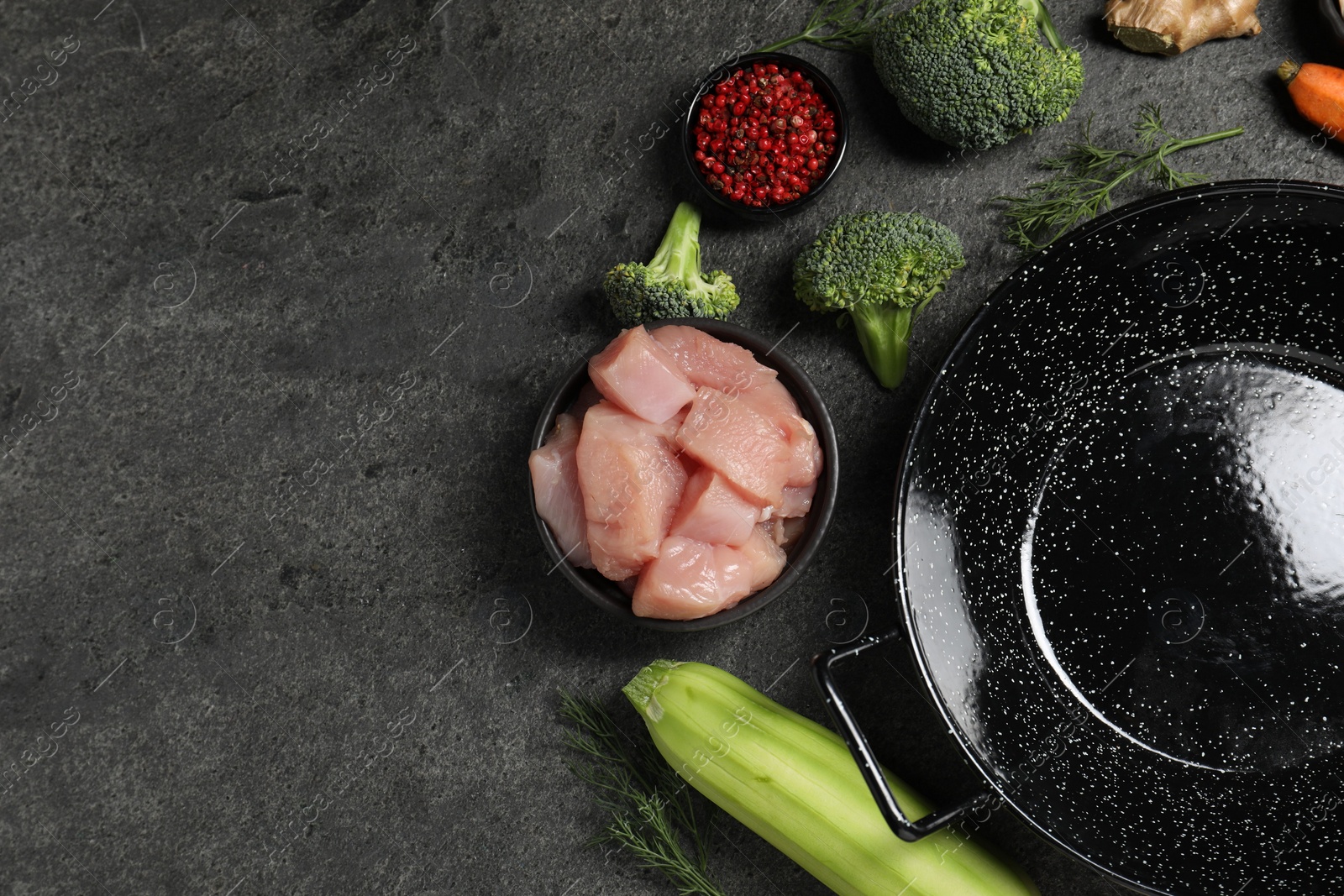 Photo of Empty iron wok and raw ingredients on grey table, flat lay. Space for text