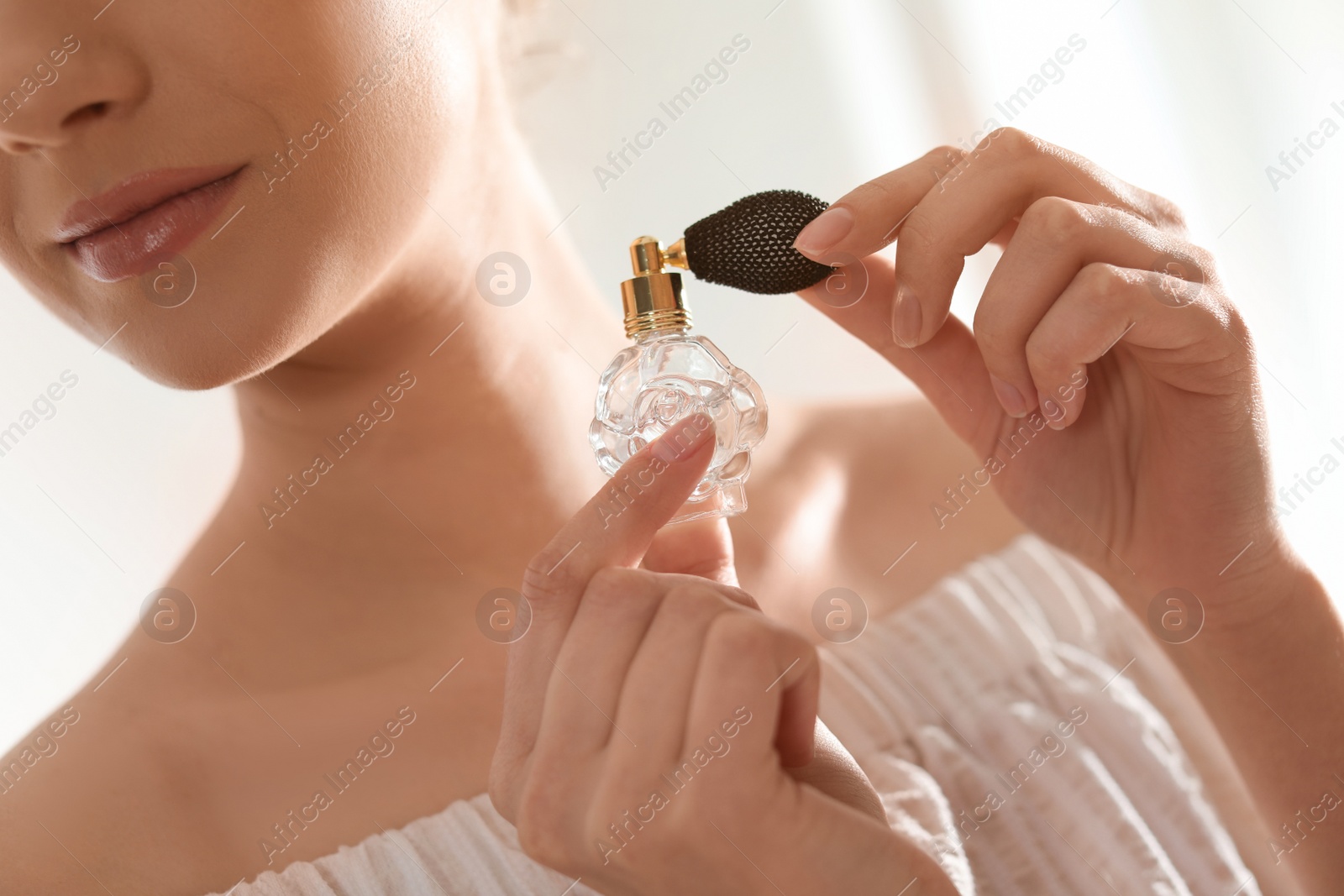 Photo of Young woman with bottle of perfume on blurred background, closeup