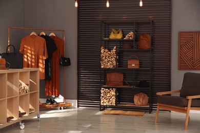 Photo of Collection of stylish woman's bags and clothes in modern boutique