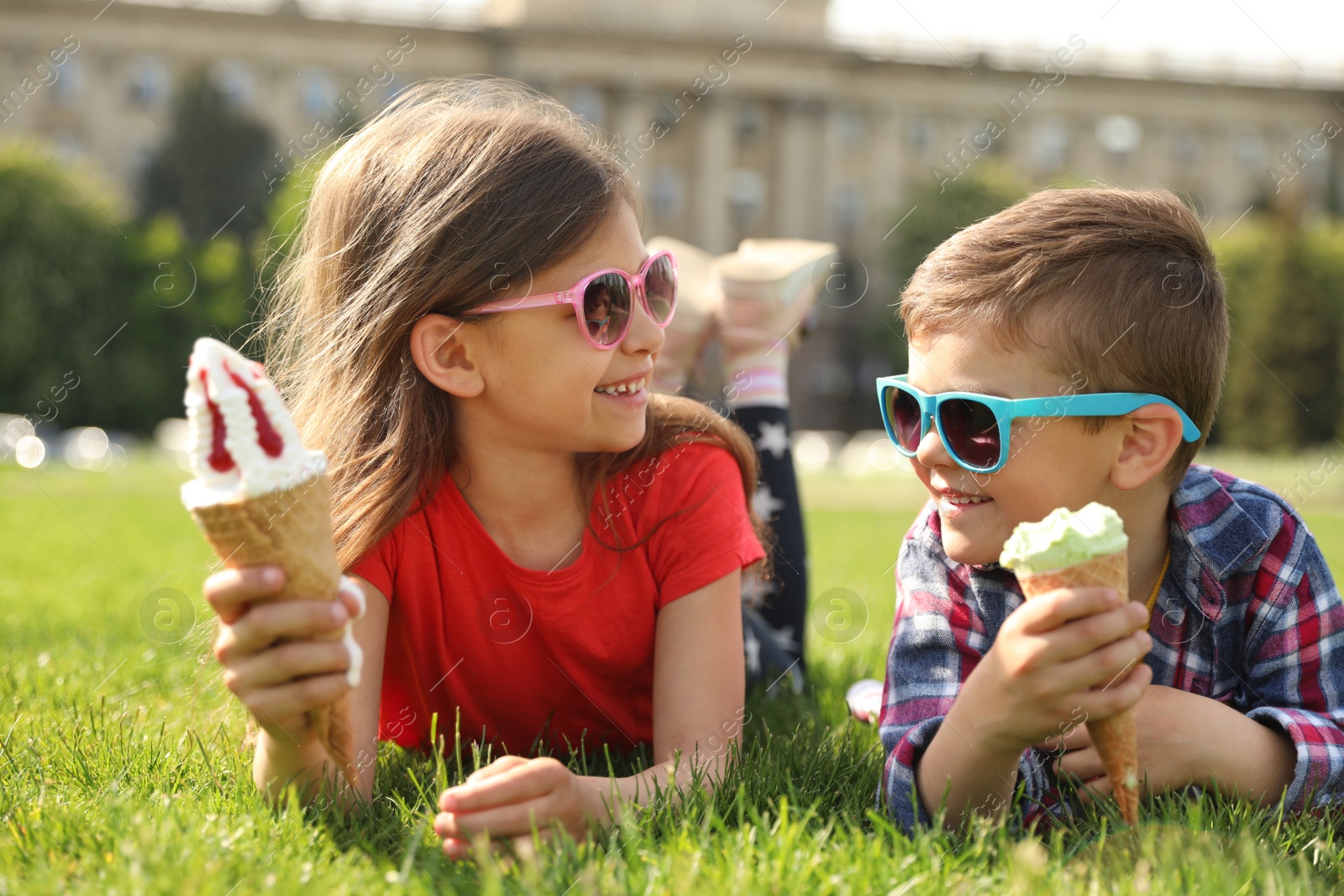 Photo of Cute children with delicious ice creams on grass outdoors