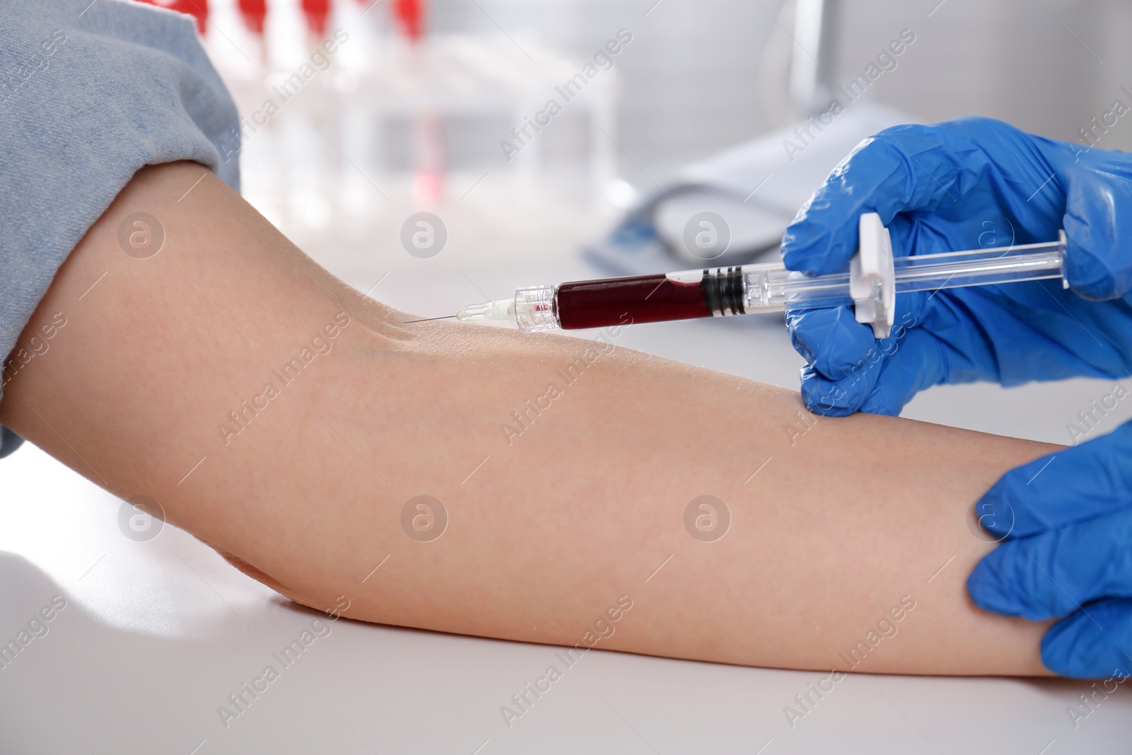 Photo of Nurse drawing blood sample from patient in clinic, closeup