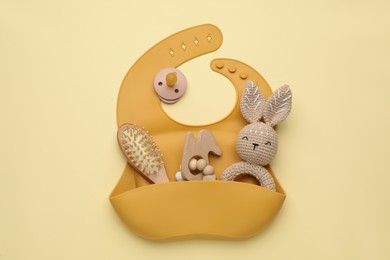 Baby accessories and bib on yellow background, flat lay