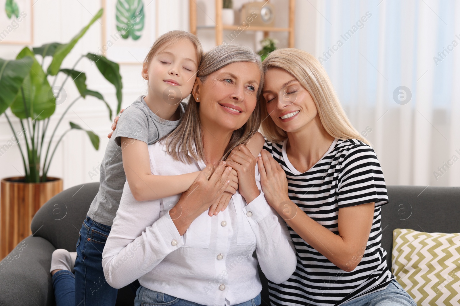 Photo of Three generations. Happy grandmother, her daughter and granddaughter at home