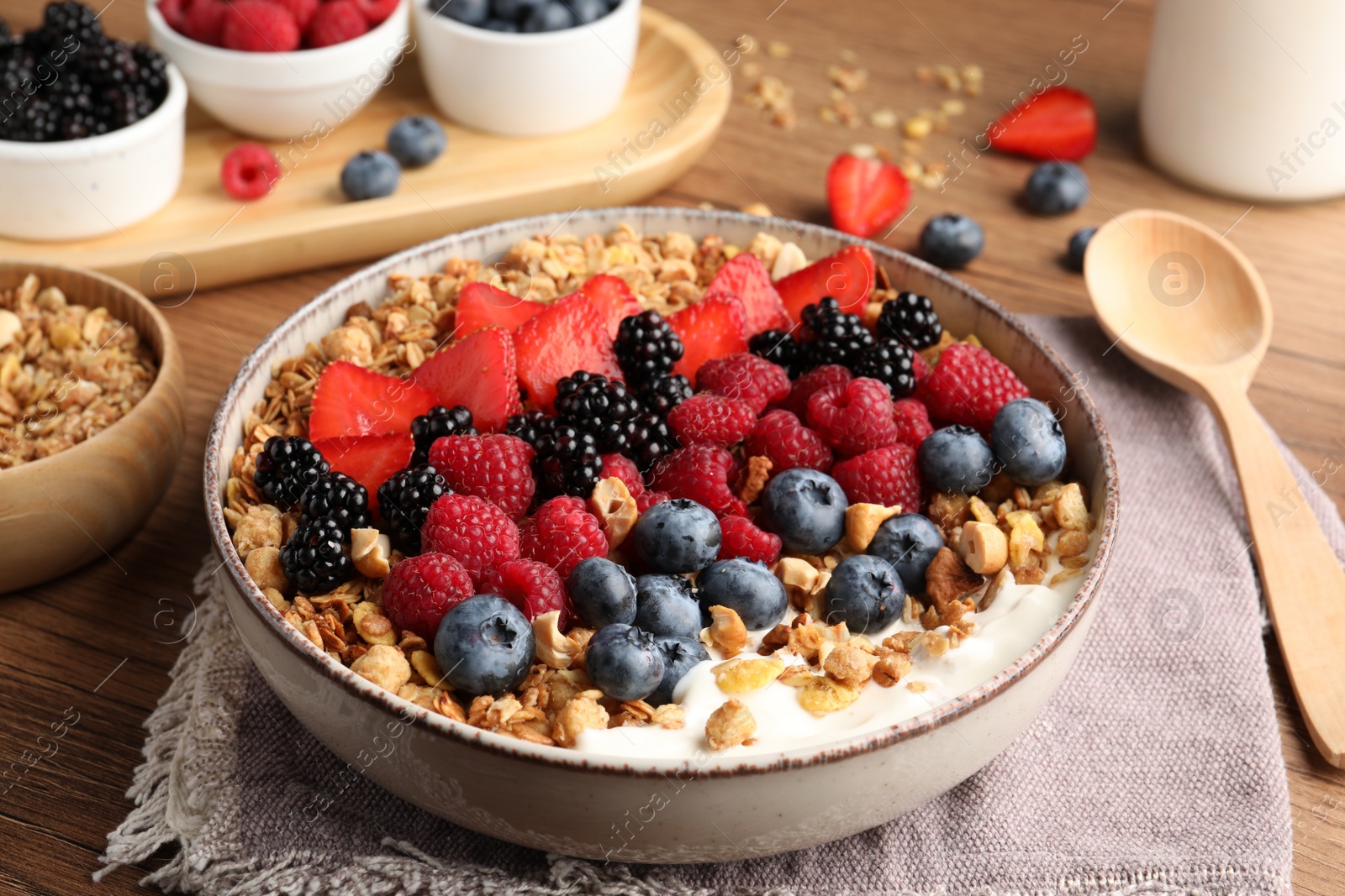 Photo of Healthy muesli served with berries on wooden table, closeup