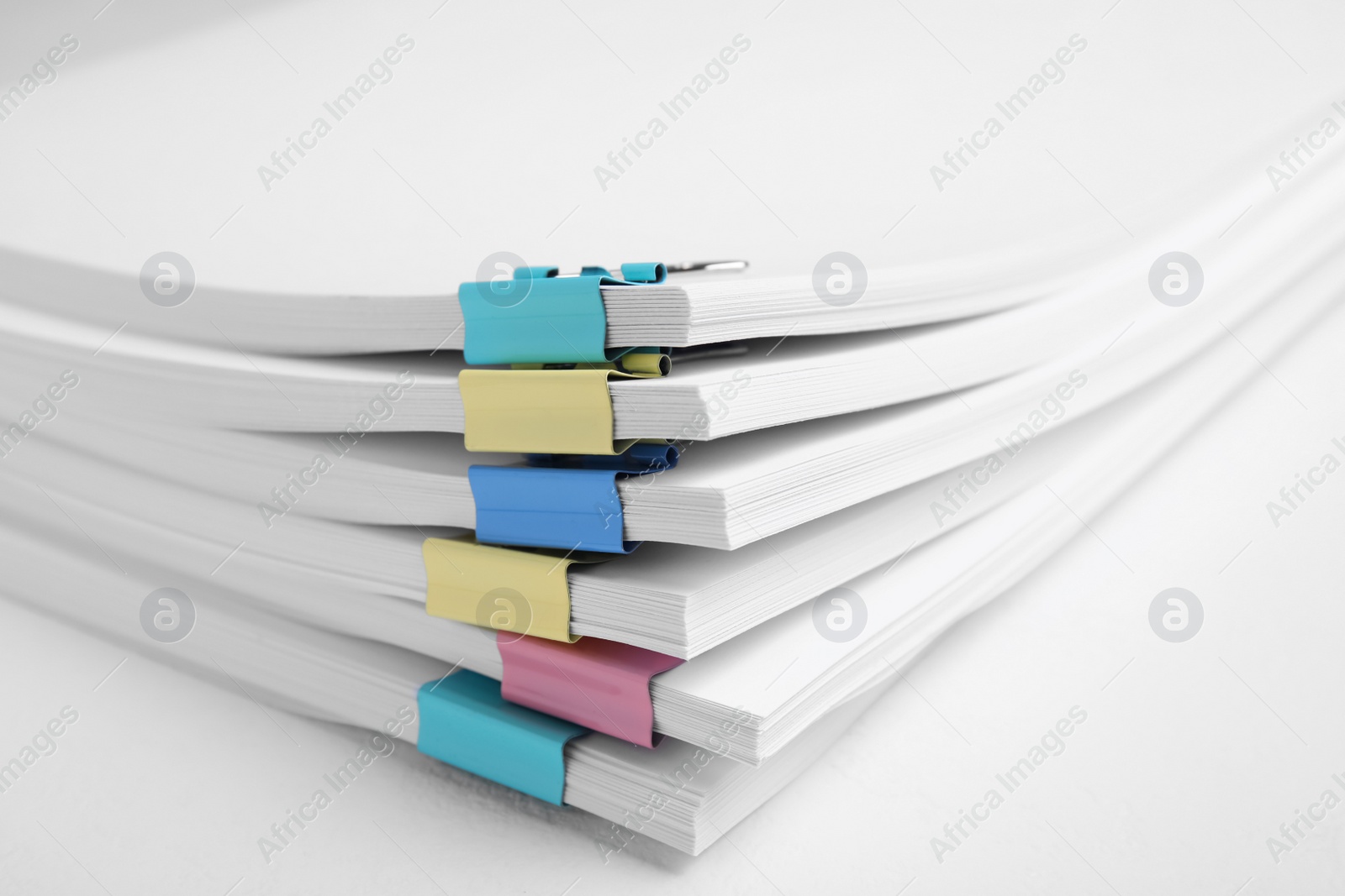 Photo of Many sheets of paper with colorful clips on white background, closeup