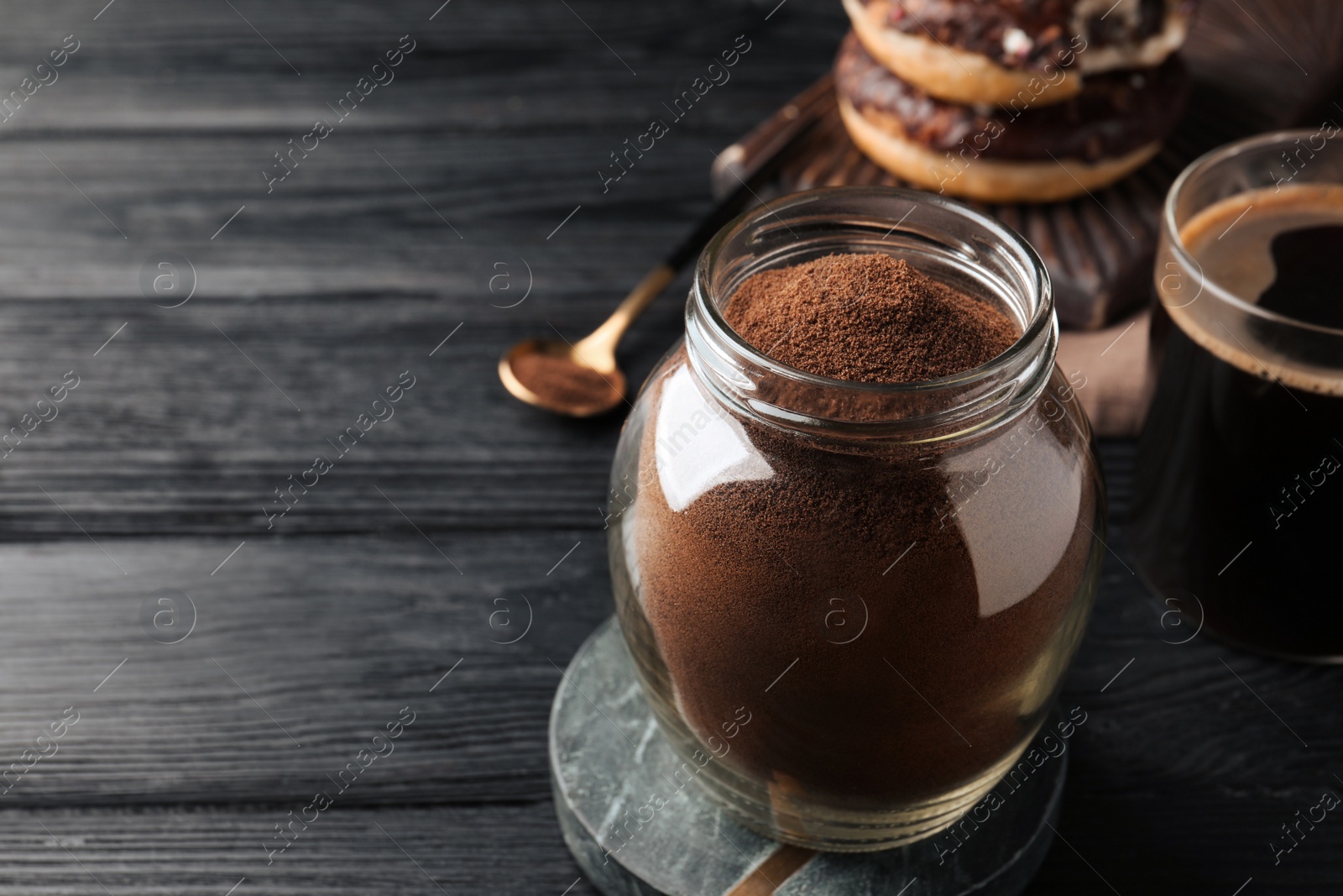 Photo of Jar of instant coffee on black wooden table. Space for text