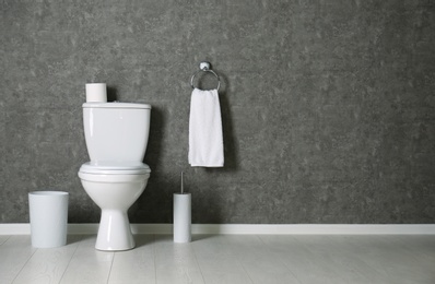 Simple bathroom interior with new toilet bowl near grey wall. Space for text