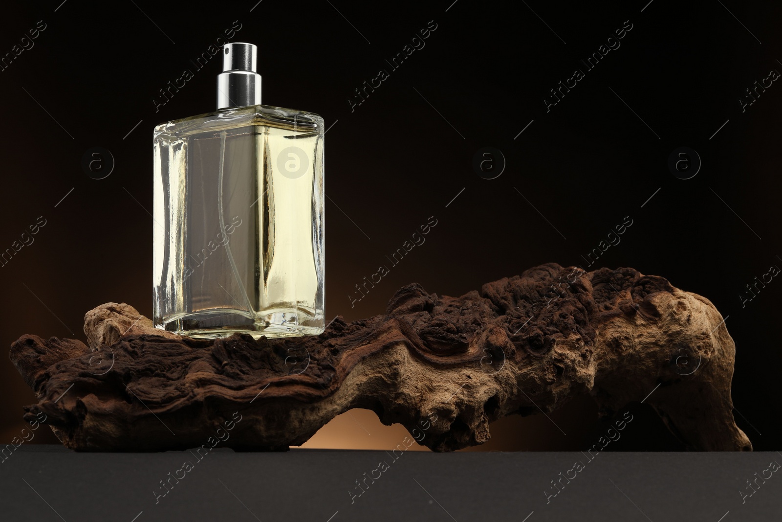 Photo of Luxury men`s perfume in bottle on grey table against dark background, space for text