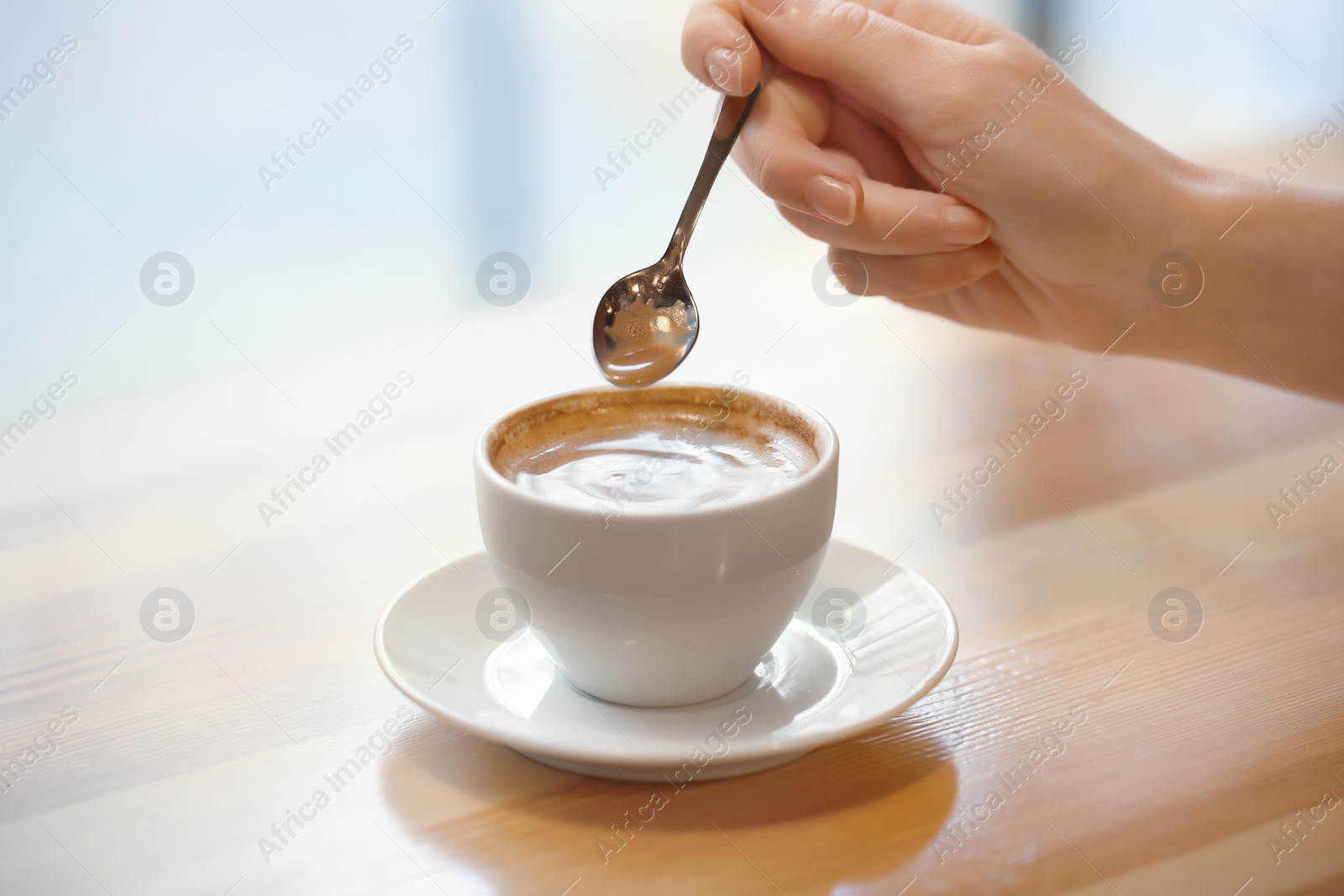 Photo of Woman with cup of aromatic coffee at wooden table