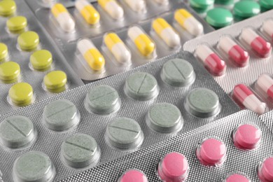 Many blisters with different pills as background, closeup