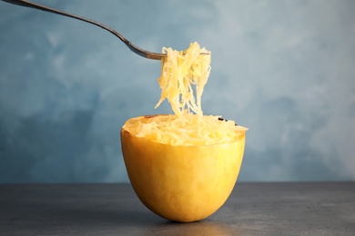 Photo of Fork with flesh over cooked spaghetti squash on table