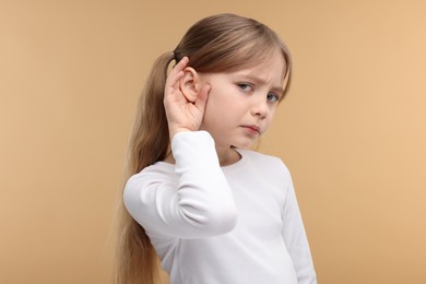 Photo of Little girl with hearing problem on pale brown background