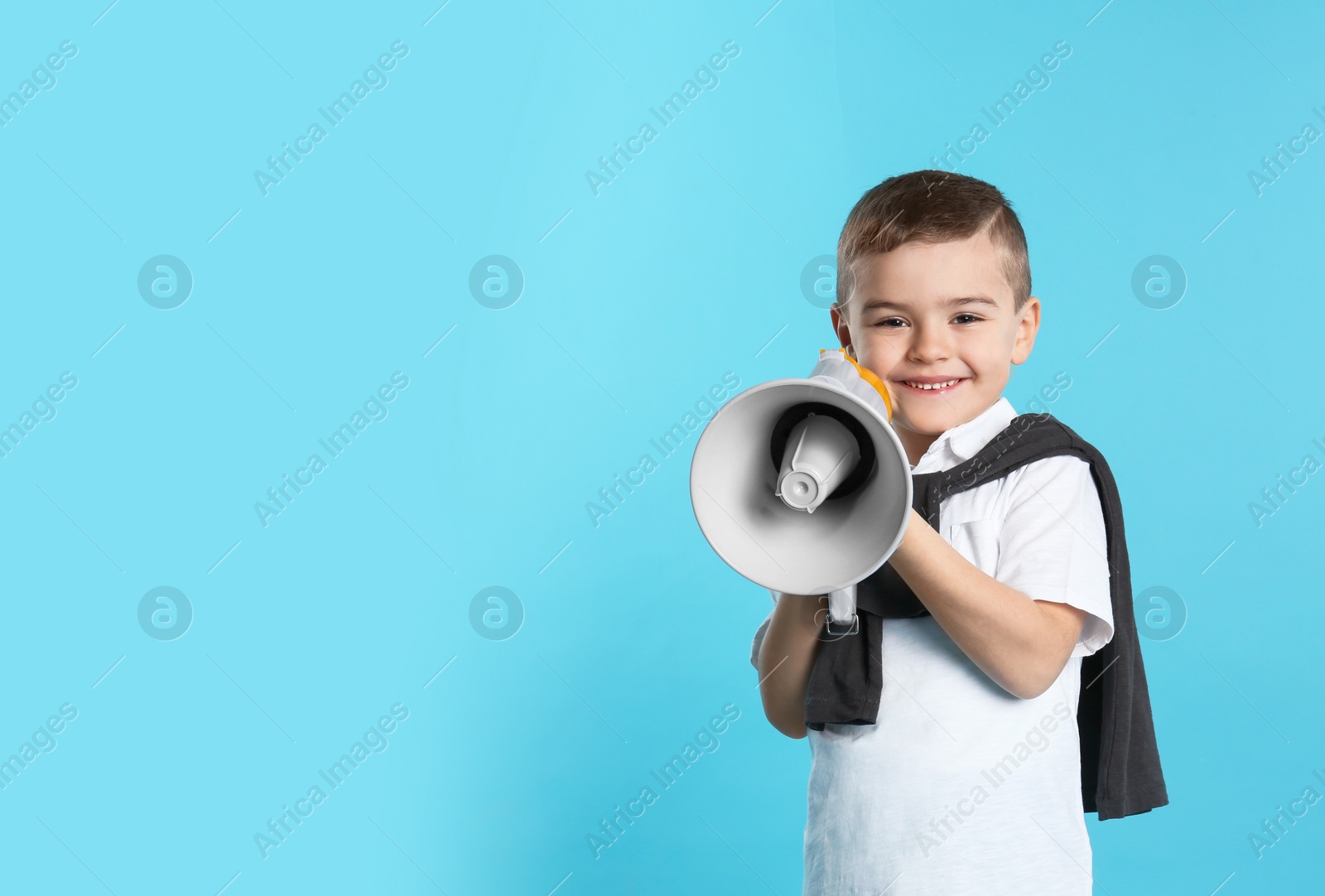 Photo of Cute funny boy with megaphone on color background. Space for text