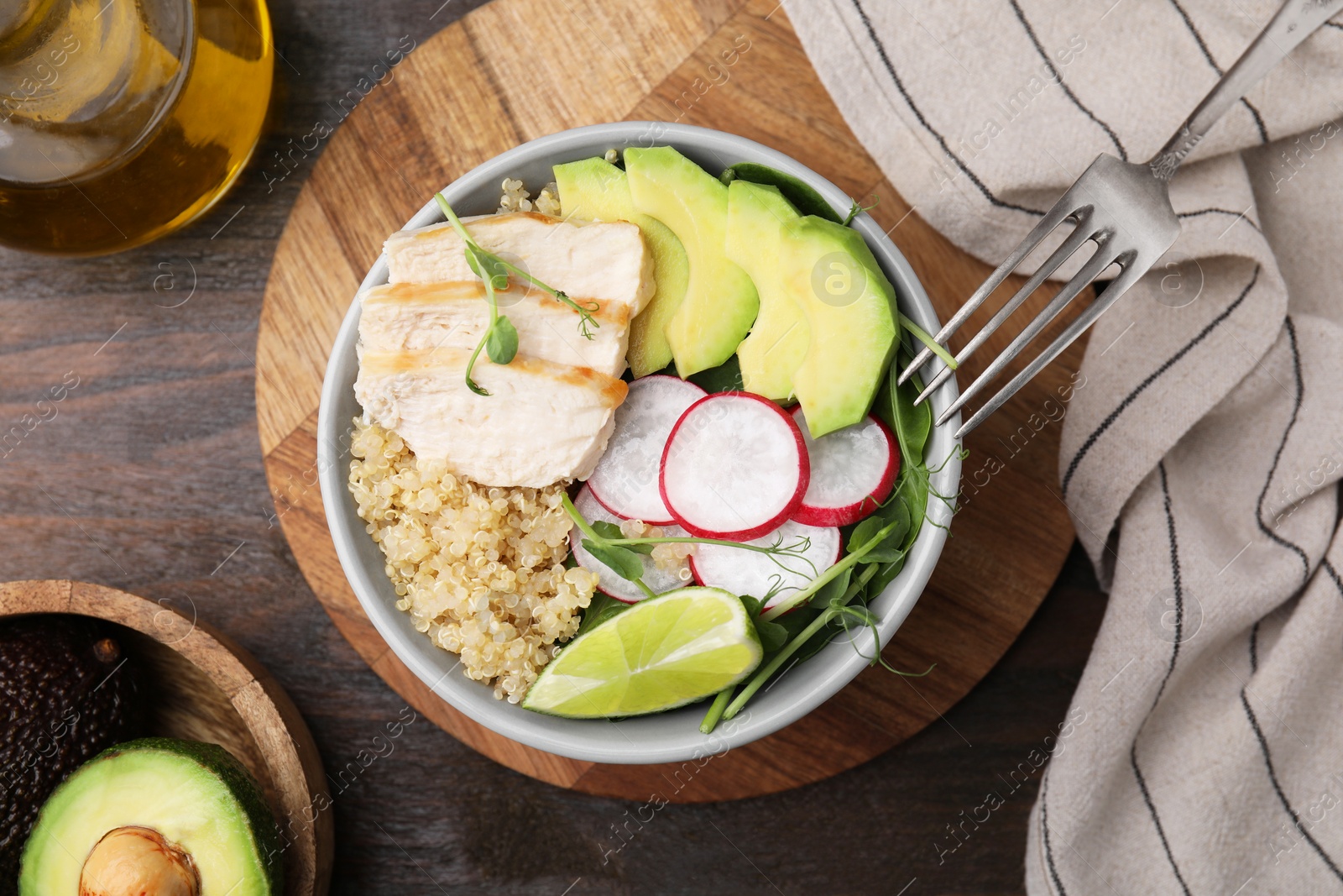 Photo of Delicious quinoa salad with chicken, avocado and radish served on wooden table, flat lay