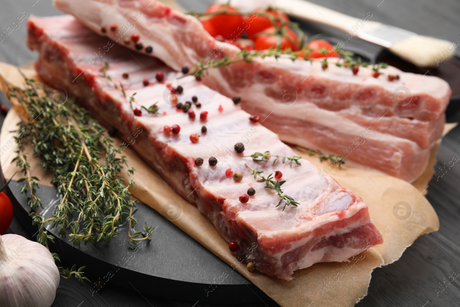 Photo of Raw pork ribs with thyme and peppercorns on table, closeup