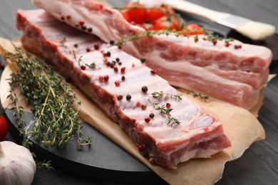 Raw pork ribs with thyme and peppercorns on table, closeup