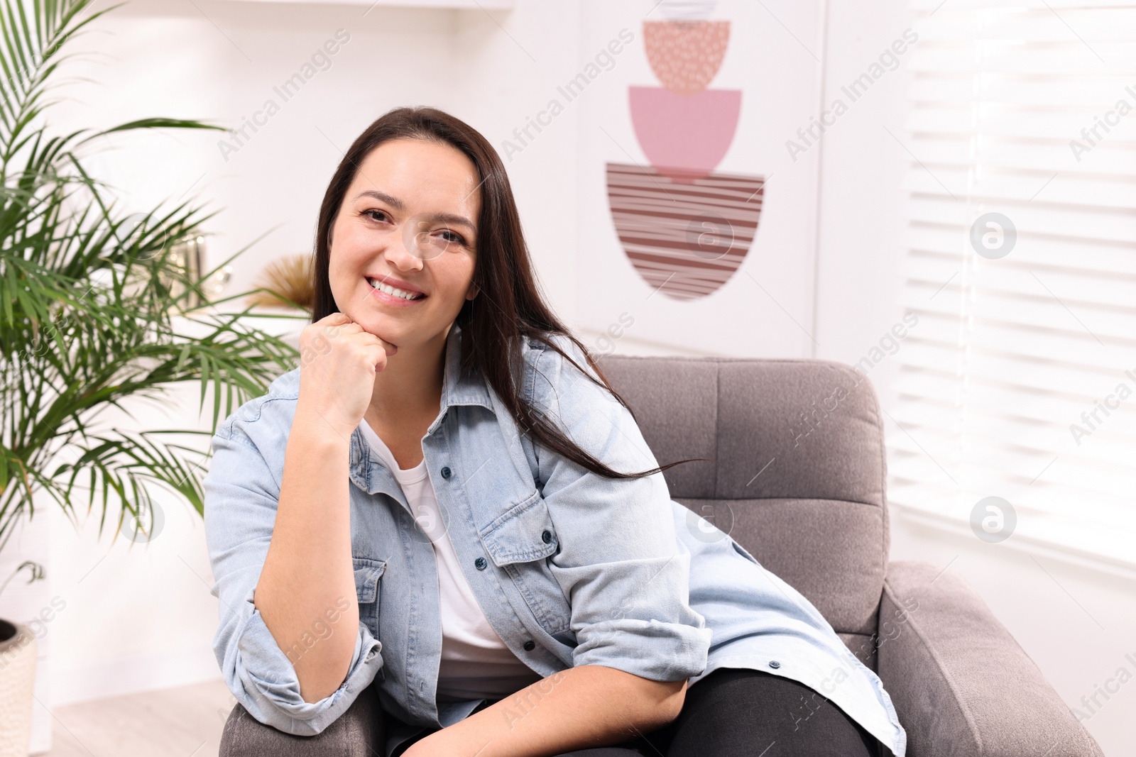 Photo of Beautiful overweight woman sitting in armchair at home