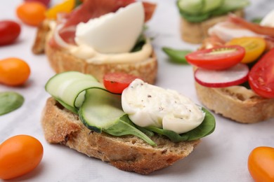 Photo of Delicious sandwich with burrata cheese, cucumber and tomato served on white table, closeup