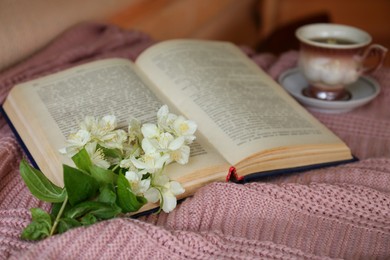 Photo of Beautiful jasmine flowers, open book and cup of aromatic drink on pink fabric