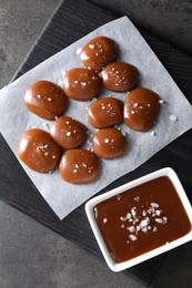 Tasty candies, caramel sauce and salt on grey table, top view