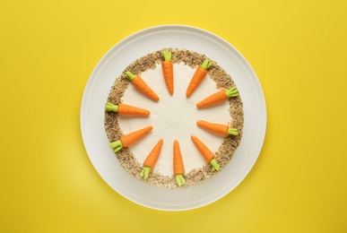 Dish with tasty carrot cake on yellow background, top view