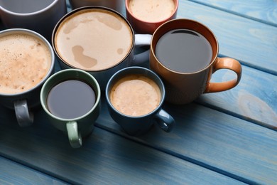 Photo of Many cups of different coffee drinks on light blue wooden table