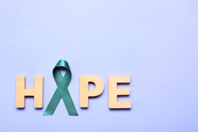 Photo of Word Hope made of wooden letters and teal awareness ribbon on lilac background, top view. Symbol of social and medical issues