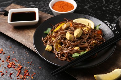 Photo of Stir-fry. Tasty noodles with vegetables and meat served on dark textured table