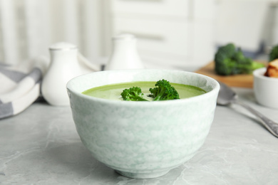 Photo of Delicious broccoli cream soup served on grey marble table indoors