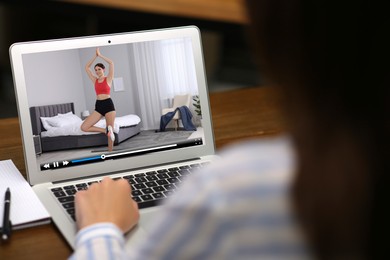 Image of Woman watching morning exercise video on laptop at table, closeup