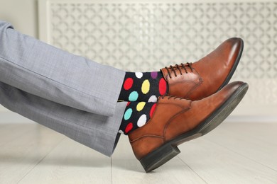 Photo of Man wearing stylish shoes and colorful socks indoors, closeup