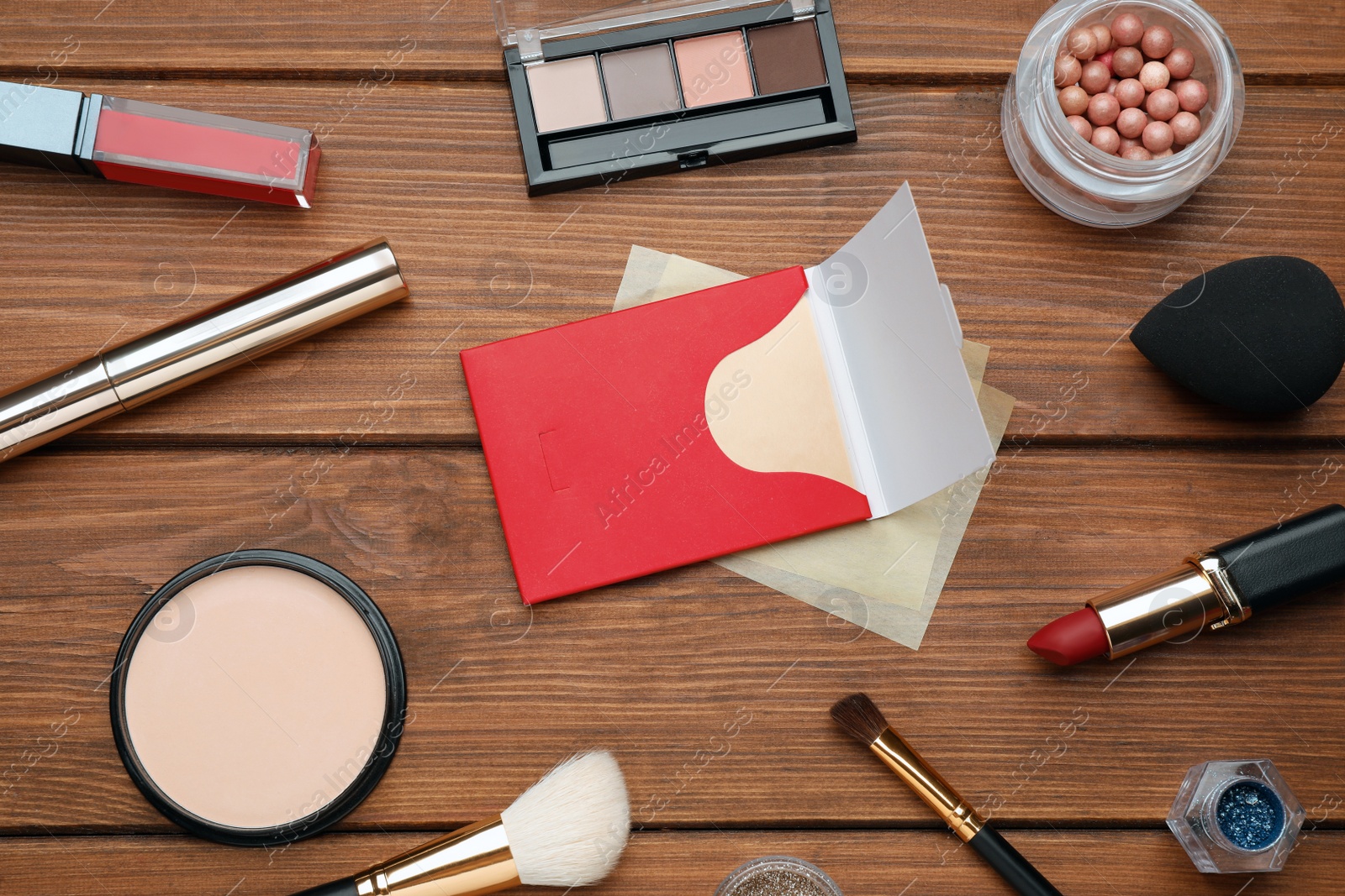 Photo of Facial oil blotting tissues and different decorative cosmetics on wooden table, flat lay. Mattifying wipes