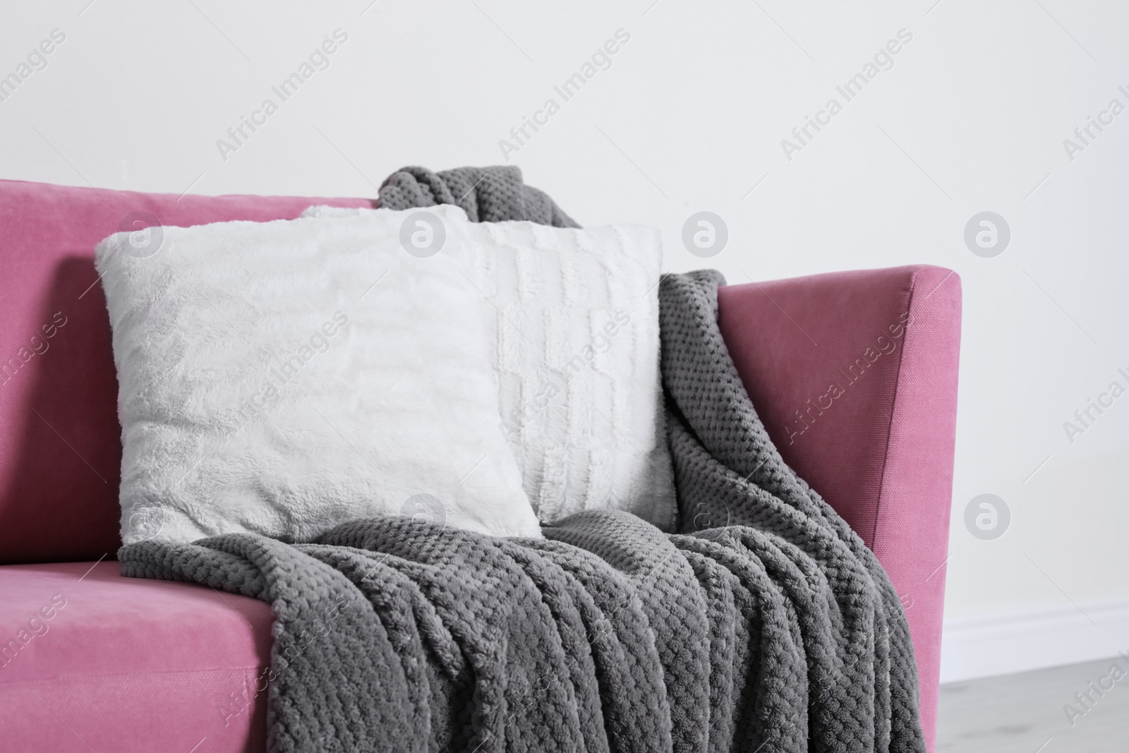 Photo of Cozy sofa with pillows and plaid near light wall. Idea for living room interior design