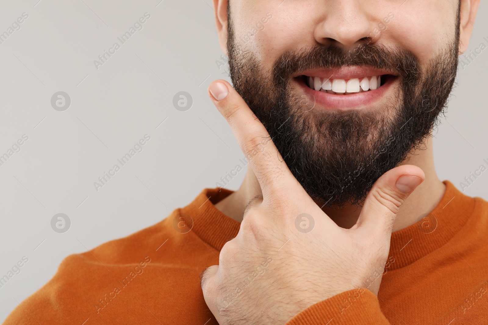 Photo of Man with clean teeth smiling on gray background, closeup. Space for text