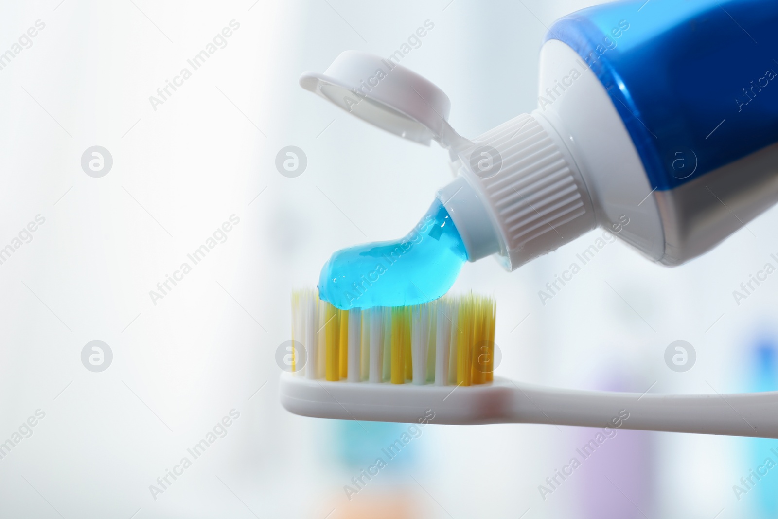 Photo of Applying toothpaste on brush against blurred background, closeup