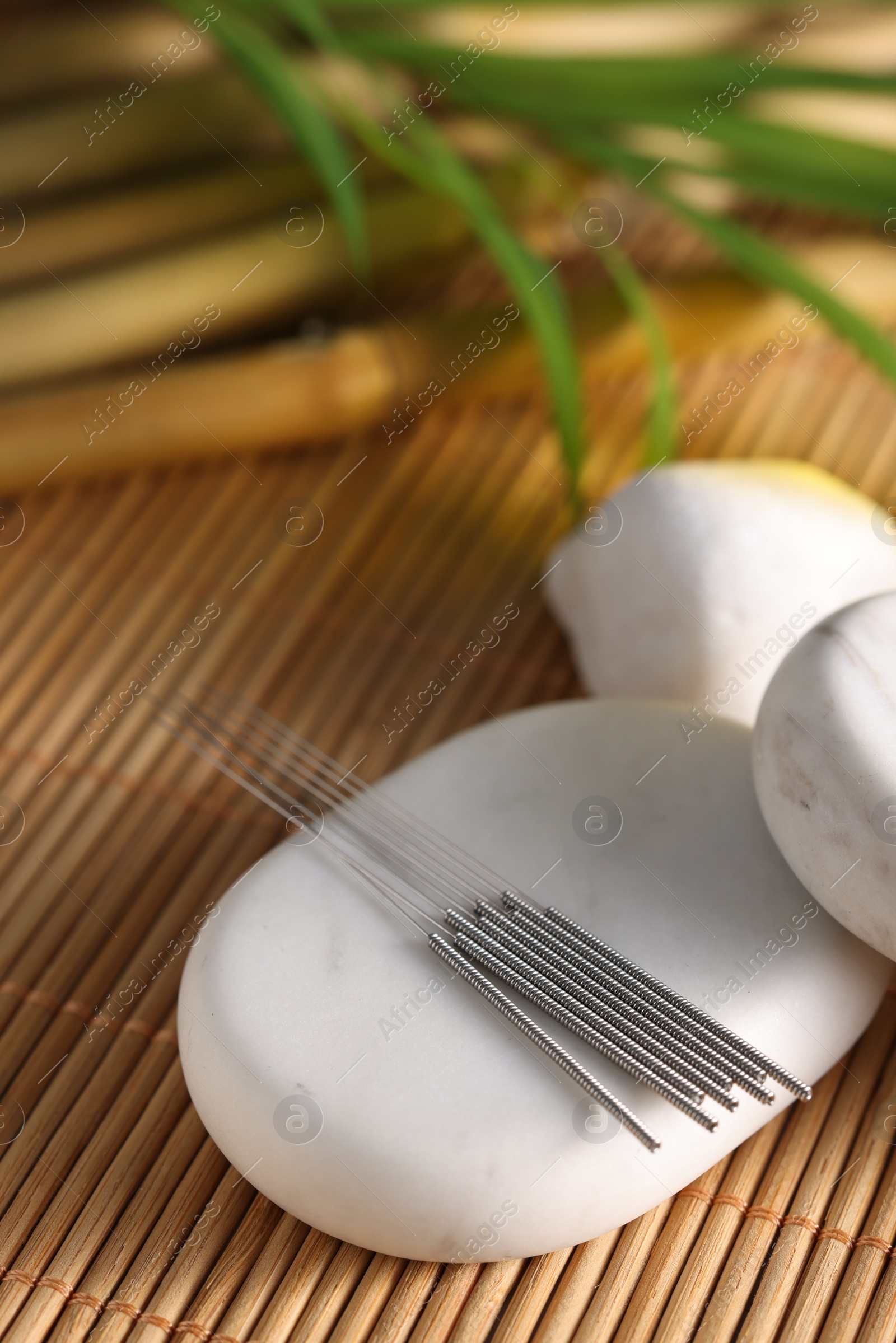 Photo of Acupuncture needles and spa stones on bamboo mat