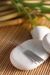 Photo of Acupuncture needles and spa stones on bamboo mat