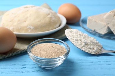 Different types of yeast, eggs, dough and flour in spoon on light blue wooden table
