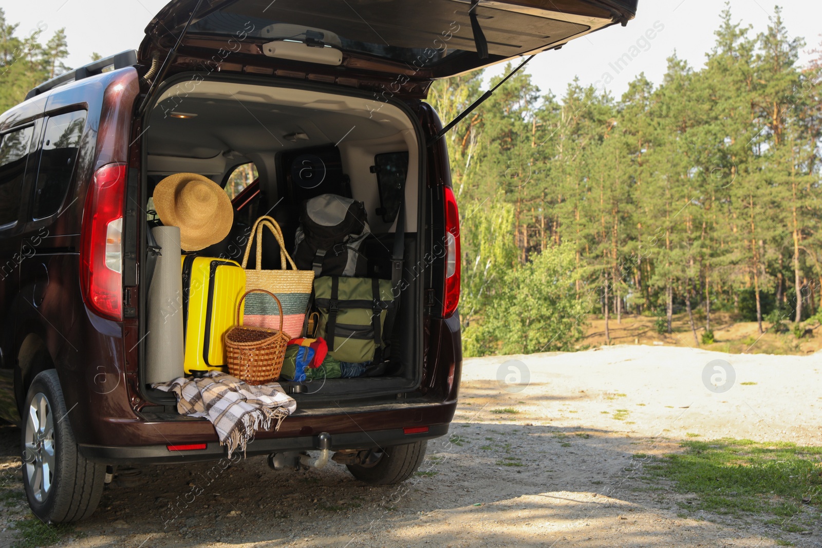 Photo of Van with camping equipment in trunk outdoors