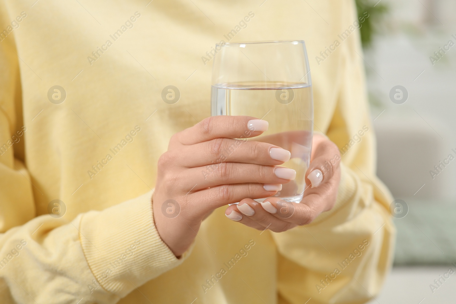 Photo of Healthy habit. Woman holding glass with fresh water indoors, closeup