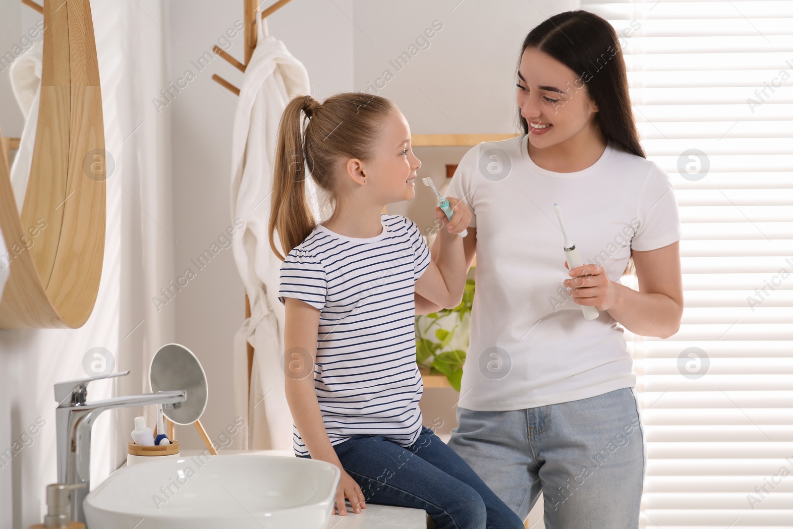 Photo of Mother and her daughter brushing teeth together in bathroom