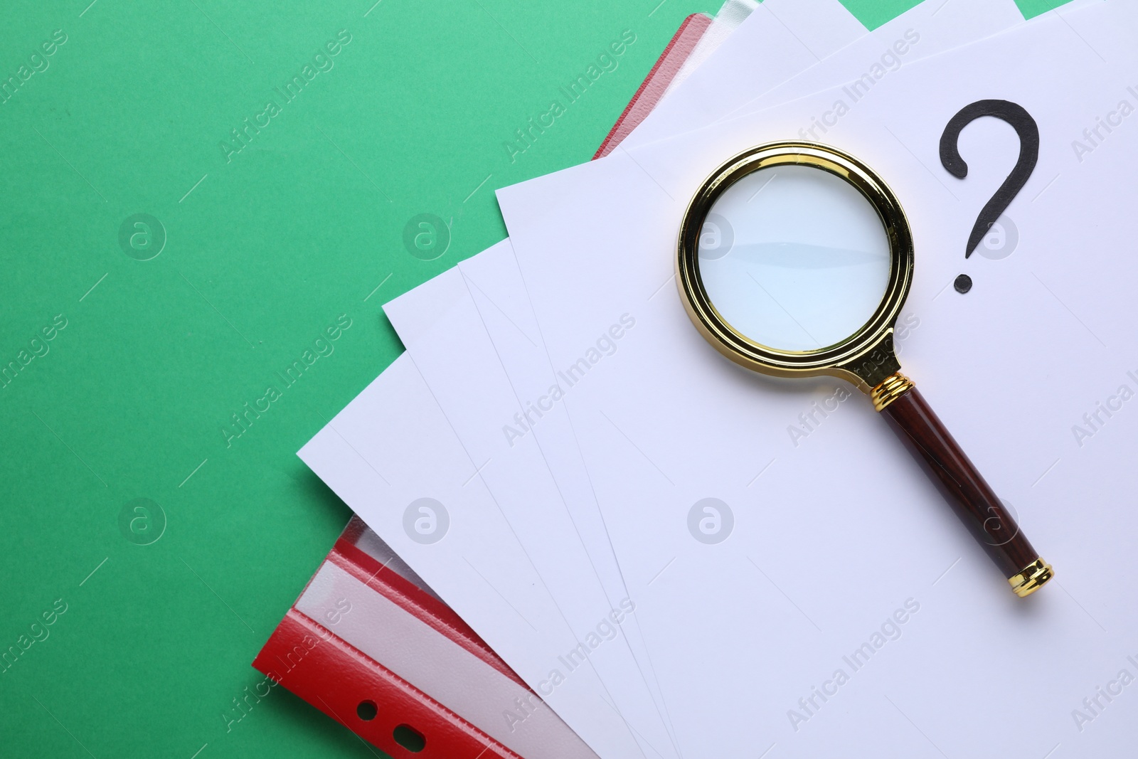 Photo of Magnifying glass, folder with paper sheets and question mark on green background, top view