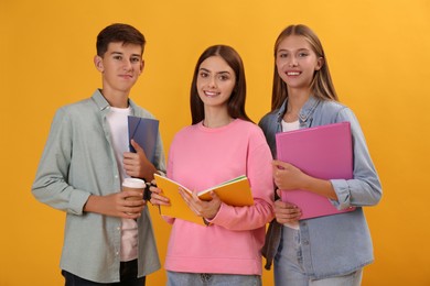 Group of teenage students with stationery on yellow background