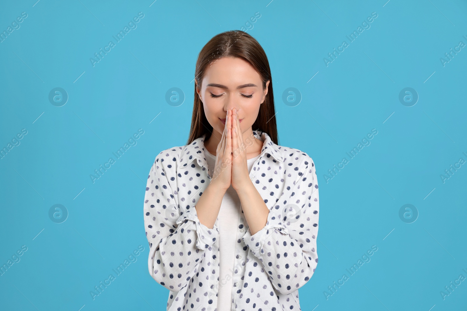 Photo of Woman with clasped hands praying on turquoise background