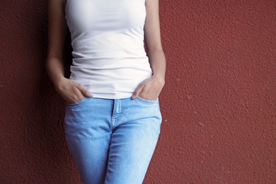 Photo of Young hipster woman in stylish jeans posing near color wall