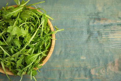 Fresh arugula on blue wooden table, top view. Space for text