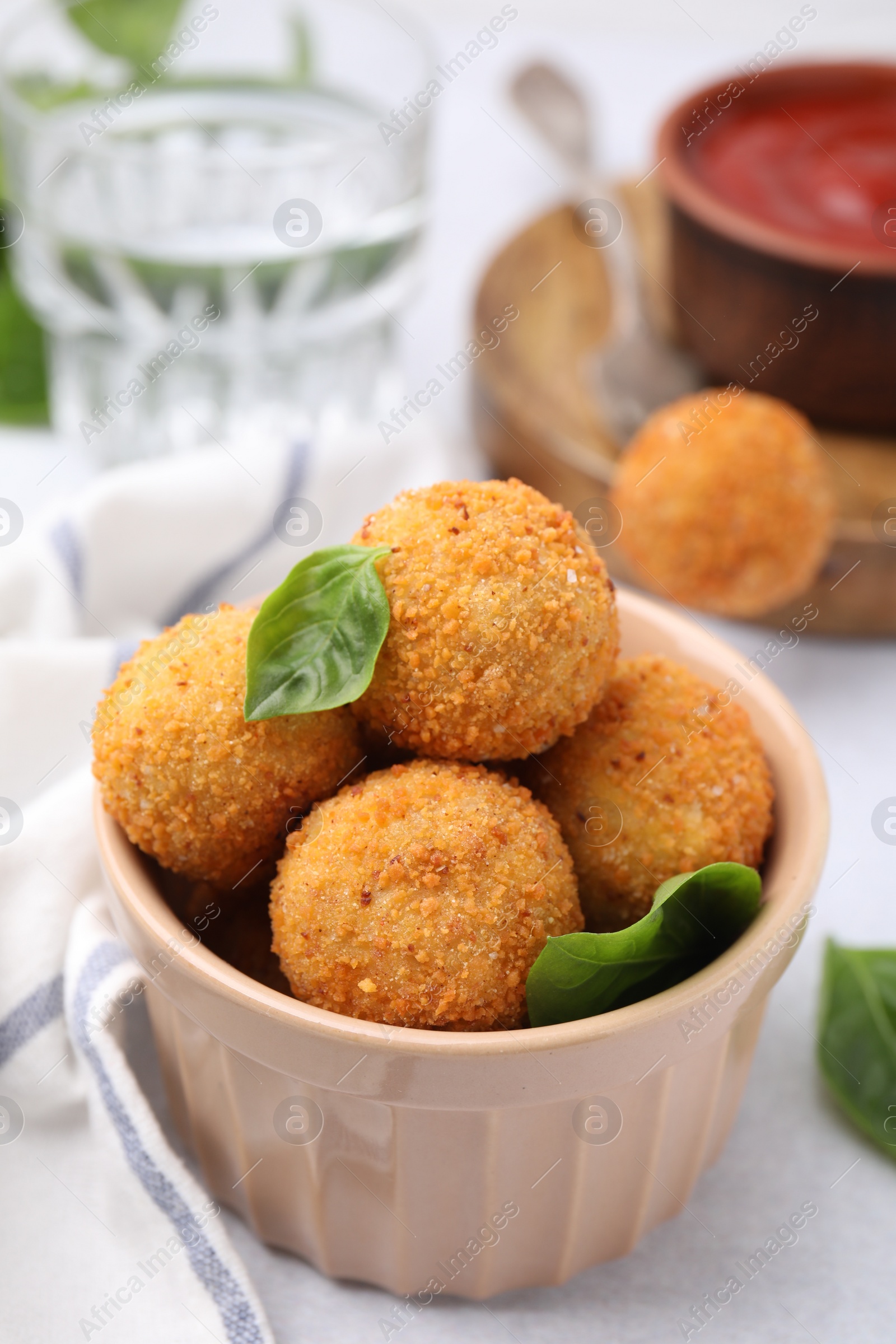 Photo of Bowl of delicious fried tofu balls with basil on white table, closeup