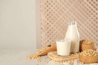 Photo of Fresh soy milk and beans on light grey table, space for text